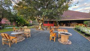 a patio with tables and chairs and a tree at OneSeasonFarm Chiangsaen in Chiang Saen