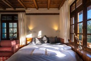 a bedroom with a bed and a chair and windows at Timberwolves Vintage Manali in Manāli