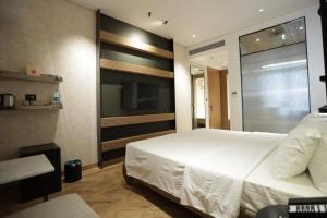 a bedroom with a large white bed and a tv at Regency Hotel Malabar Hill in Mumbai +11 photos