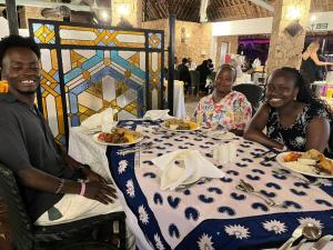three people sitting at a table with plates of food at Kiwis home in Nakuru