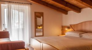 ein Schlafzimmer mit einem Bett und einem großen Fenster in der Unterkunft Hotel Ai Pini in Vigo di Fassa