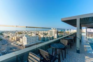 a balcony with chairs and tables on a building at Jarzez Inn Hotel Azaiba فندق جرزيز إن العذيبة in Muscat