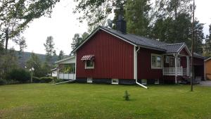 een rood huis in een tuin met een groen gazon bij Nordic character in Vidsel