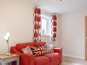 a red couch in a living room with a window at The Old Dairy in Nether Broughton