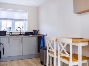 a kitchen with white cabinets and a table and chairs at The Old Dairy in Nether Broughton
