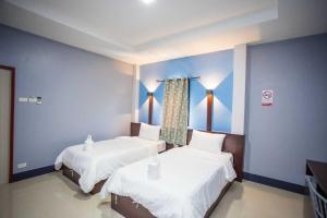 two beds in a room with blue walls at Nakarin Hotel in Amnat Charoen