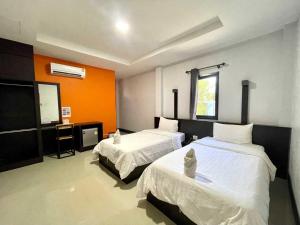 a bedroom with two beds and an orange wall at Nakarin Hotel in Amnat Charoen