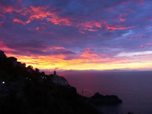 a sunset over the ocean with a building on a hill at Locanda Degli Agrumi in Conca dei Marini