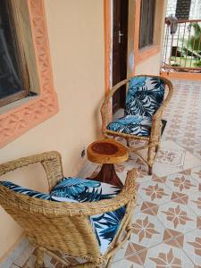 two wicker chairs and a table on a patio at milina homes in Ukunda