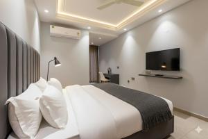 a bedroom with a large white bed and a flat screen tv at Hotel Xotic Avenue in Gurgaon