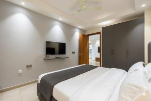 a bedroom with a white bed and a flat screen tv at Hotel Xotic Avenue in Gurgaon +6 photos