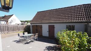 a patio with a table and chairs in front of a house at Allis Kajüte - Entspannen im großen Garten oder vorm Kamin in Lübeck