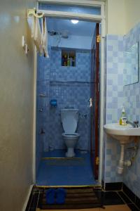 a blue tiled bathroom with a toilet and a sink at Kajole Homestay in Kakamega +20 photos