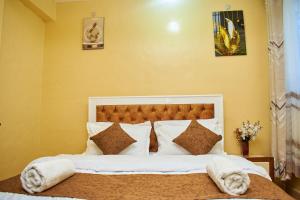 a bedroom with a large bed with white sheets and pillows at Kajole Homestay in Kakamega