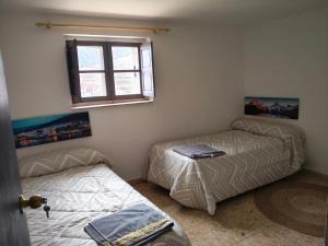 two beds in a room with a window at La posada del Mozarabe in Alquife
