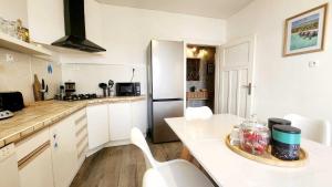 a kitchen with white cabinets and a table and a refrigerator at Refuge des Rêves in Amnéville +20 photos
