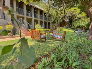 three chairs and a table in the yard of a building at Amoris Guesthouse - Waterkloof ridge in Pretoria