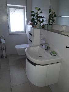 a white bathroom with a sink and a toilet at Ferienwohnung Arthur in Luckenwalde +5 photos
