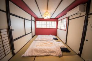 a bed in a room with red walls and windows at カモンイン 稲荷 in Kyoto