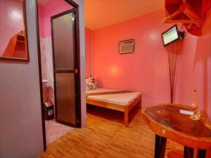 a small room with a bed and a table in it at OYO 622 Butterfly Totem Guesthouse in Puerto Princesa City