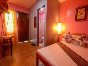 a bedroom with pink walls and a bed and a table at OYO 622 Butterfly Totem Guesthouse in Puerto Princesa City +5 photos