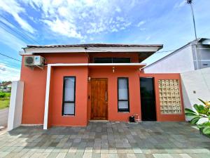 a small red house with a dog sitting in front of it at Tio Homestay in Praya