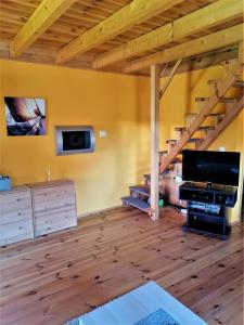 a living room with a television and a staircase at Kruklanki Domek in Kruklanki