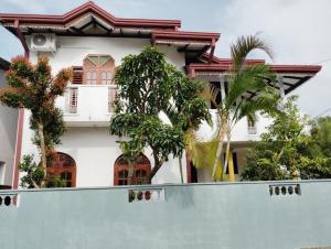 a white house with trees behind a fence at Green View in Ambalangoda