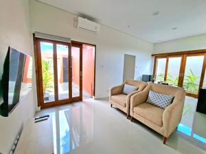 a living room with two chairs and windows at Tio Homestay in Praya