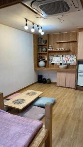 a room with a table and a kitchen with wooden floors at 명파아트호텔 in Chŏjil-li