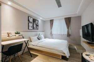 a bedroom with a bed and a desk and a television at Meworld Hotel - Zhongshan in Taipei