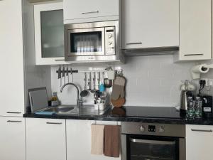 a kitchen with white cabinets and a sink and a microwave at Oriole Havana Salalah in Salalah +4 photos