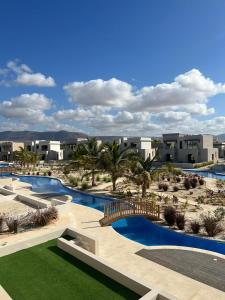a resort with two pools and palm trees and buildings at Oriole Havana Salalah in Salalah