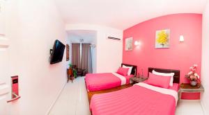 a pink room with two beds and a tv at Hotel O Vince Villa in Bukit Mertajam
