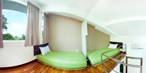 a room with two green beds and a window at Hotel O Vince Villa in Bukit Mertajam +16 photos