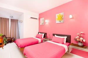 two beds in a room with pink walls at Hotel O Vince Villa in Bukit Mertajam