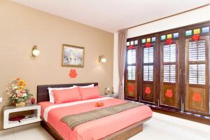 a bedroom with a pink bed and some windows at Hotel O Vince Villa in Bukit Mertajam