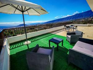 a balcony with chairs and a table and an umbrella at Finca Hoya del Pino in Arafo