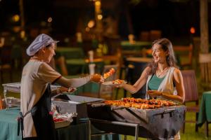 a woman is handing a woman a plate of food at Hintok River Camp in Sai Yok