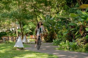 a woman riding a bike down a path at Hintok River Camp in Sai Yok