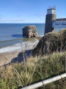 a rock in the ocean next to a lighthouse at 3 Bedroom Apartment near the Beach in South Shields