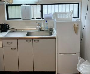 a small kitchen with a sink and a refrigerator at 丸亀 Sawau 丸亀駅まで徒歩8分 うどん屋まで徒歩1分 5名まで宿泊可駐車場 1台有 港近 in Marugame