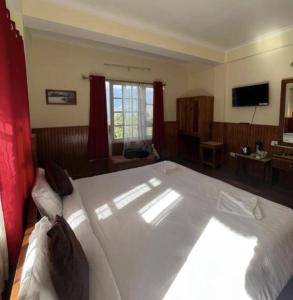 a bedroom with a large white bed with red curtains at Ifseen Villa in Pelling
