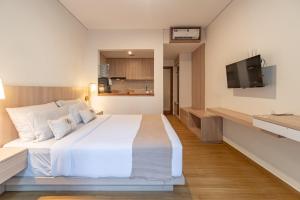 a bedroom with a large white bed and a flat screen tv at The Hita Apartement in Seminyak