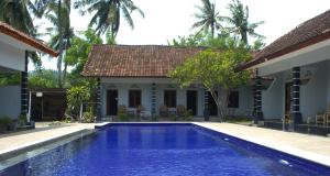 a villa with a swimming pool in front of a house at Sawe Homestay in Kuta Lombok