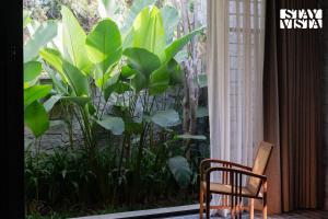 a chair in front of a window with a plant at StayVista at Matchbox with Pet-Friendly, BBQ & Lawn in Hosūr +39 photos
