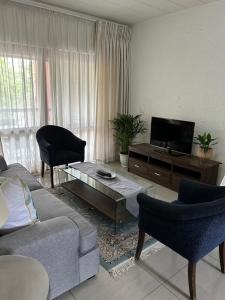 a living room with a couch and a flat screen tv at Alendo Apartments in Johannesburg