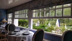 a restaurant with tables and chairs and a large window at LOGIS - Hôtel & Restaurant Le Gonfalon in Germigny-lʼEvêque