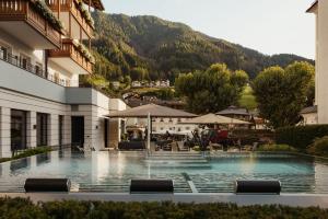 a hotel with a swimming pool with a mountain in the background at Hotel Genziana in Ortisei