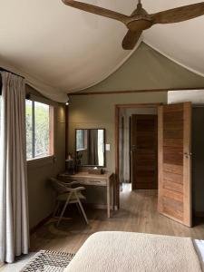 a bedroom with a ceiling fan and a desk at Mkhuze Trails Lodge in Hluhluwe